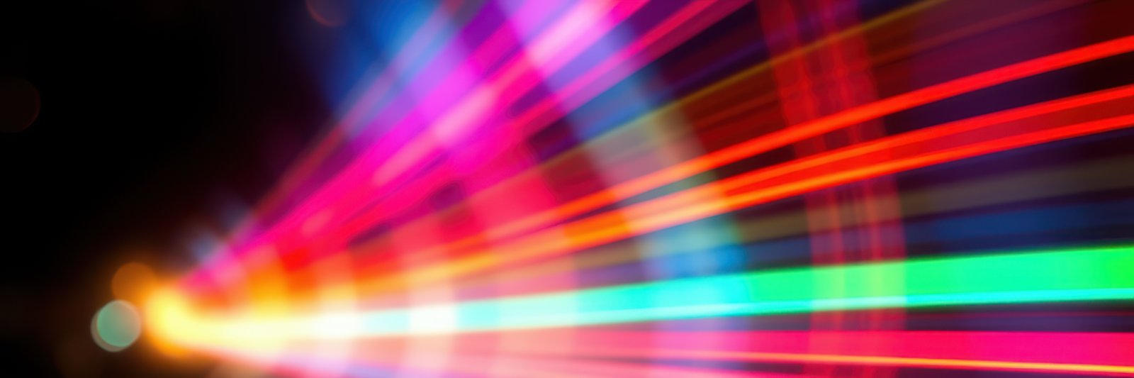 Colorful light streaks blurring across a dark background create a vibrant visual display at night